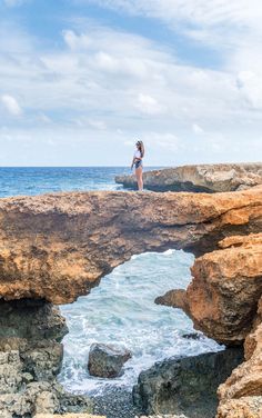 a woman standing on top of a cliff near the ocean