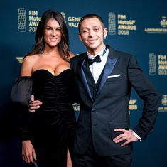 a man and woman standing next to each other in front of a blue wall at an event