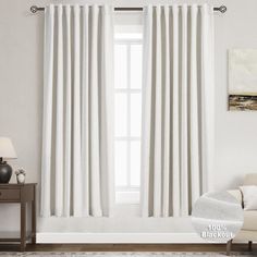 a white curtain hanging on the side of a window next to a chair and table