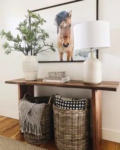 a table with two baskets and a painting on the wall above it in a room