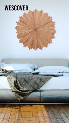 a bed sitting on top of a wooden floor next to a wall mounted art piece