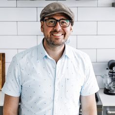 a man wearing glasses and a hat standing in a kitchen