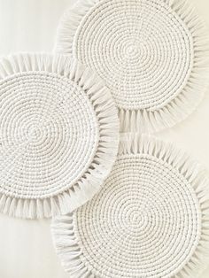 three white woven placemats with tassels on them