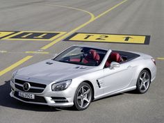 a silver mercedes slk convertible driving down a race track with the driver's seat up