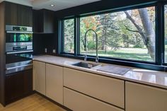 a modern kitchen with large windows and stainless steel appliances