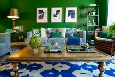 a living room with green walls and blue couches in front of a coffee table