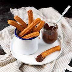 some churro sticks are on a plate next to a jar of ketchup