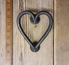 a heart shaped iron hook on a wooden wall