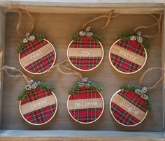 four ornaments in a box with the words merry and plaid on them, hanging from twine