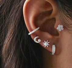 a woman wearing three different ear piercings with stars and moon designs on her ears