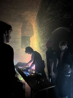 three people standing in front of a dj's turntable at a dark room