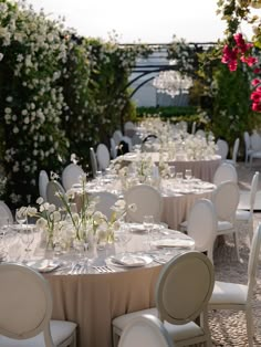 tables and chairs are set up for an outdoor wedding reception with white flowers on the table