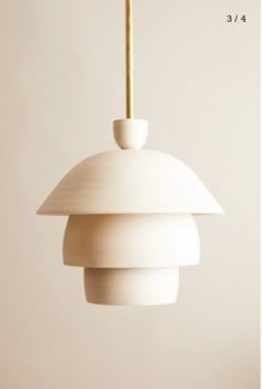 a white light hanging from a ceiling fixture with a wooden stick sticking out of it