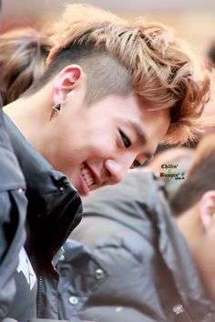 a young man is smiling and looking at his cell phone while wearing ear studs