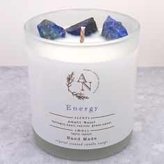 a candle with rocks in it sitting on a table next to a white container that says energy