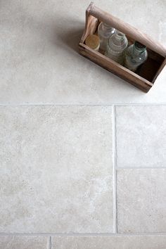 a wooden box with bottles in it sitting on the floor next to a tile floor