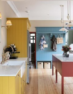 a kitchen with yellow cabinets and white counter tops next to an island in the middle