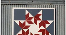 a red, white and blue quilt hanging on the side of a building