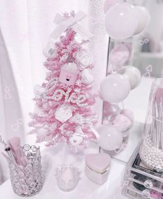 a pink christmas tree surrounded by white balloons and other decorations on a table in front of a mirror