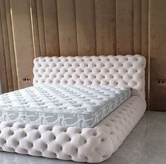 a white bed sitting in the middle of a room next to a wall with wooden paneling