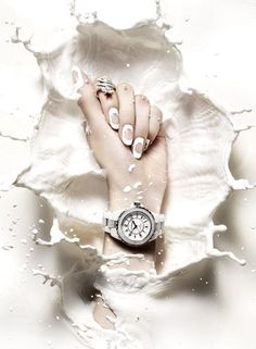 a woman's hand with two rings on her wrist, surrounded by water droplets