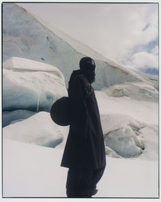 a man standing in the snow with his back to the camera, wearing a black coat