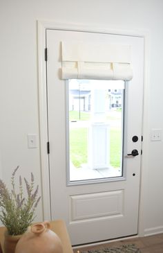 a white door with a window and vase on the side table in front of it