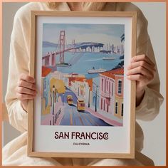 a woman holding up a framed poster with the golden gate bridge in san francisco