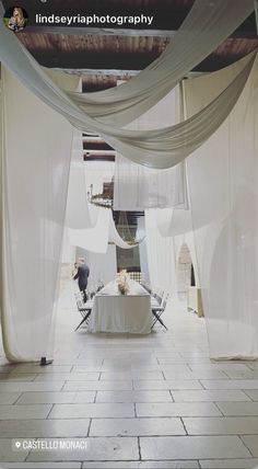 a photo taken from the inside of a room with white draping and chairs