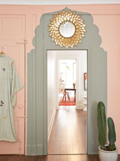 an open door leading to a hallway with a mirror on the wall and pink walls