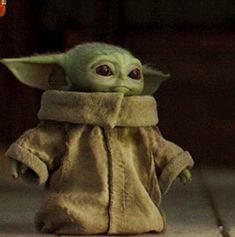 the child yoda doll is wearing a brown coat