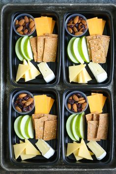 four black trays filled with different types of food and nuts on top of each other