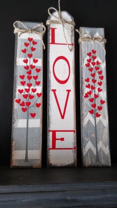 two wooden signs with red hearts tied to them on top of a fireplace mantel