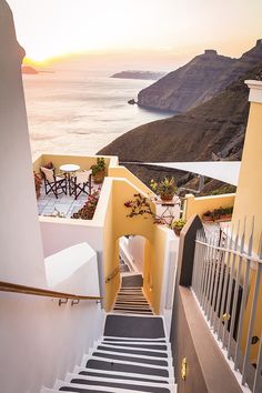 the stairs lead down to an outdoor dining area overlooking the ocean and cliffs at sunset