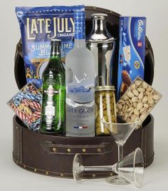 an open suitcase filled with drinks and snacks next to a wine glass on a table