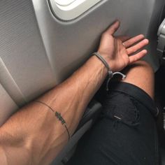 a man with his arm wrapped around the seat of an airplane, holding onto another person's wrist