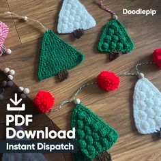 crocheted christmas tree ornaments with pom - poms hanging from string on wooden table