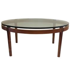 an oval glass table with wooden legs