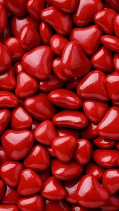 red candy hearts are piled on top of each other in this close up shot,