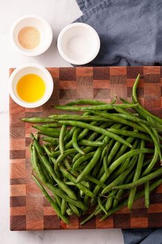 green beans are on a cutting board next to bowls