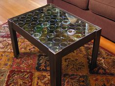 a coffee table made out of wine bottles on top of a rug in front of a couch