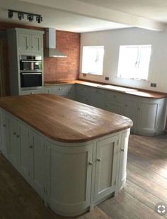 a large kitchen with an island in the middle and wooden flooring on the other side