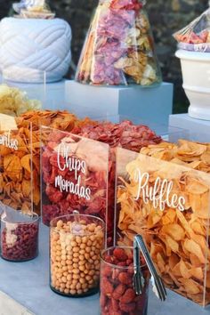 many different types of snacks on display in glass containers with names written on the bags