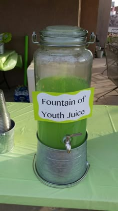 a green liquid in a glass jar with a sign on the lid that says fountain of youth juice