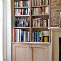 a bookshelf filled with lots of books next to a fire place