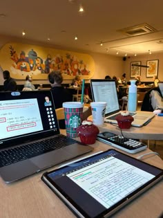 two laptops sitting on top of a wooden table next to a cup of coffee