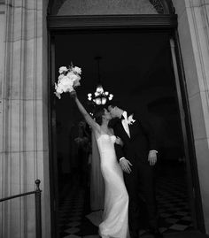 black and white photo of bride and groom exiting the church with flowers in their hand