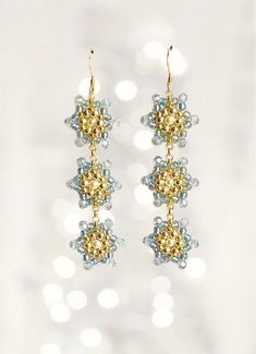 SNOWFLAKE - Snow crystals were the inspiration for these adorable 3-piece motif earrings in ice blue/gold. Material: Swarovski Elements, faceted glass beads, Miyuki/TOHO beads, 14kt gold filled ear hooks. Unique, designed and manufactured by me personally. Dimensions: l = 6.5 cm including ear hooks b = 2 cm The item will be carefully packaged in a gift box. Snow Crystal, Toho Beads, Miyuki Beads, Faceted Glass, Star Shape, 14kt Gold, Long Earrings, Ice Blue, Gold Material