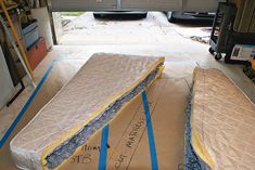 two mattresses laying on top of each other in a garage with blue tape around them