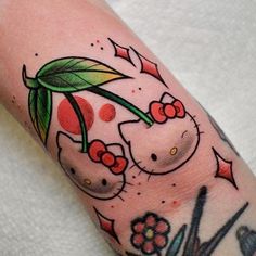 a hello kitty tattoo on the left arm and right leg, with cherries hanging from it